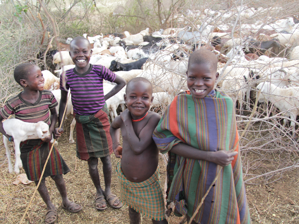 Karamajong children in a kraal in Karamoja are smiling while herding goats